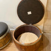 Wooden barrel-shaped pet bed with a lid on a wooden floor.