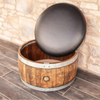 Decorative object with a dark sphere on top of a wooden barrel against a stone wall.